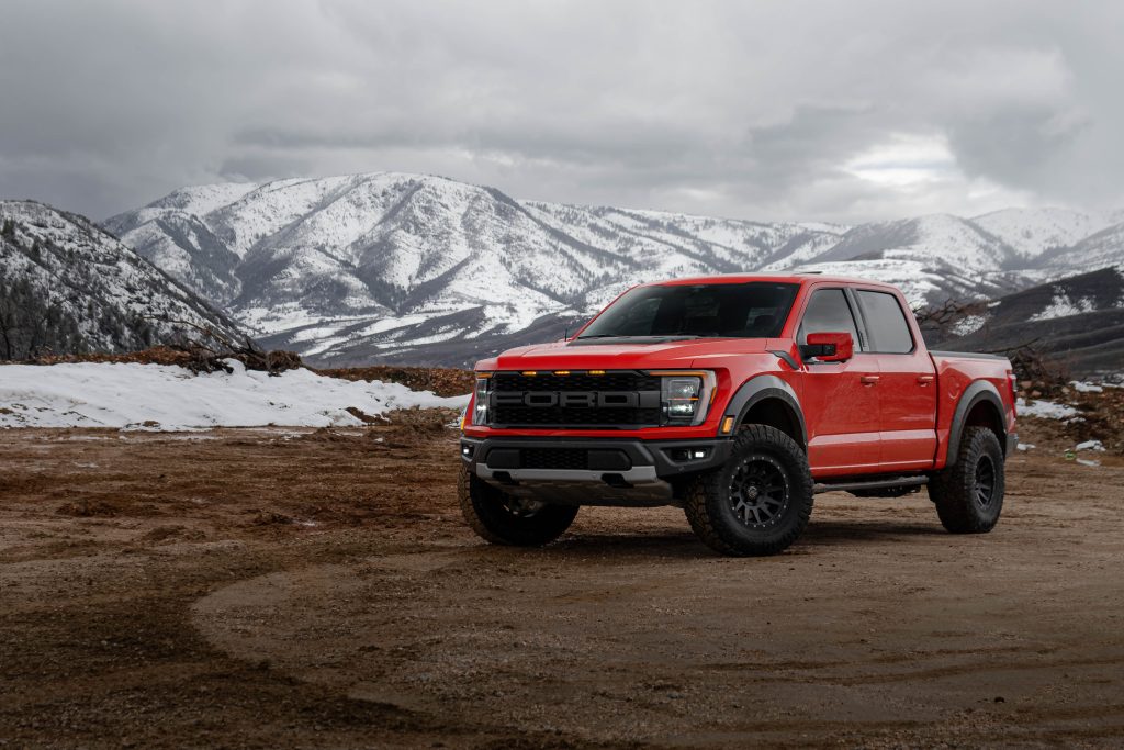 Red pickup truck parked in front of mountain scenery